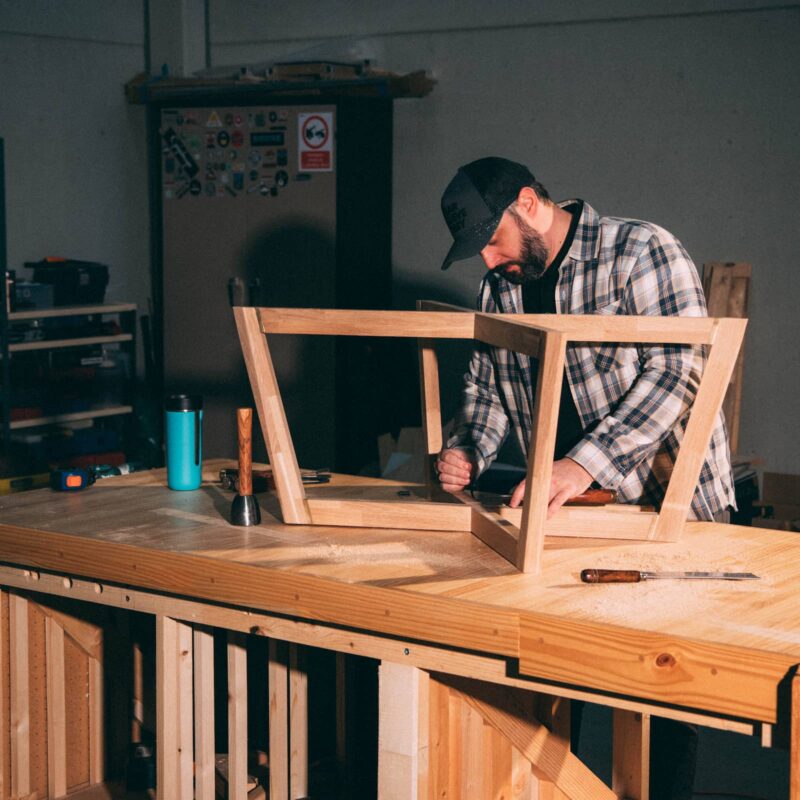 Artesano trabajando una estructura de madera maciza en su taller, respetando el ritmo del material