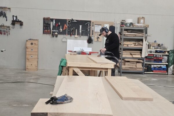 Carpintero lijando piezas de fresno macizo para un dormitorio a medida en el taller de The Wood Wolf.