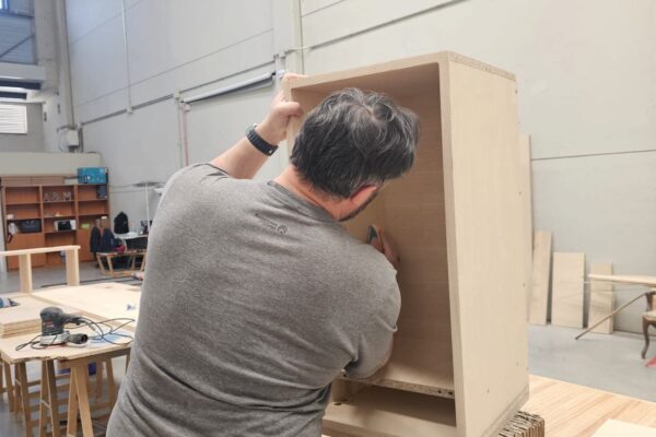 Carpintero ensamblando un módulo de madera durante la fabricación de un mueble a medida en el taller de The Wood Wolf.
