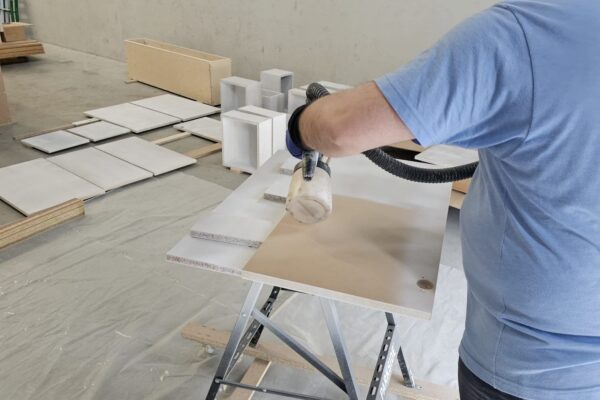 Aplicación del acabado mediante pistola HVLP sobre piezas de un mueble a medida en el taller de The Wood Wolf.