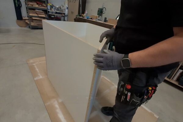 Detalle del ensamblaje y preparación de un panel lacado para un armario bajo escalera a medida fabricado por The Wood Wolf.