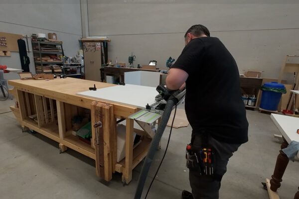 Proceso de corte de un tablero hidrófugo lacado blanco para la fabricación de un armario bajo escalera a medida en el taller de The Wood Wolf.