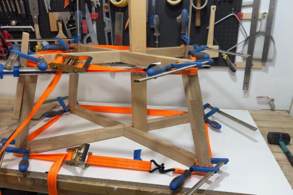 Proceso de encolado y prensado de la estructura de roble macizo durante la fabricación de una mesa de centro artesanal.