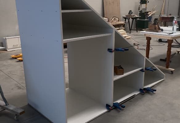 Estructura de un armario bajo escalera a medida durante el proceso de ensamblaje en el taller de The Wood Wolf.
