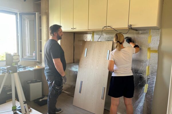 Instalación de un dormitorio a medida con armarios superiores, panel cabecero e iluminación integrada durante el montaje en la vivienda del cliente.