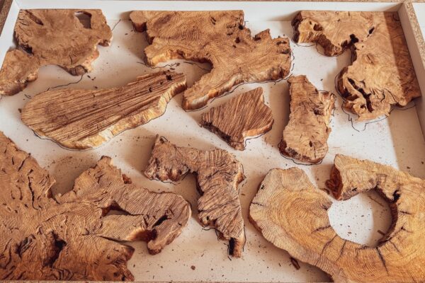 Disposición de piezas de madera de olivo durante el diseño del tablero de una mesa de centro artesanal antes del vertido de resina epoxi.