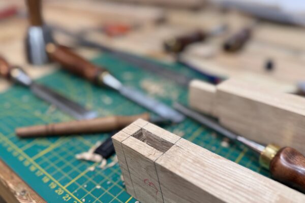 Detalle de una caja realizada a mano para una unión mediante espiga en la estructura de roble de una mesa de centro artesanal.