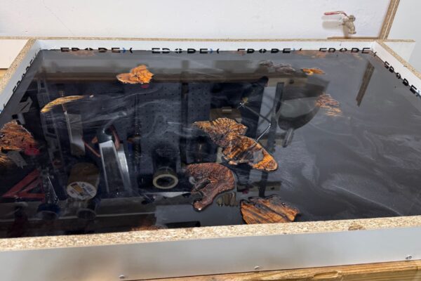 Primer vertido de resina epoxi negra durante la fabricación artesanal de una mesa de centro con madera de olivo.