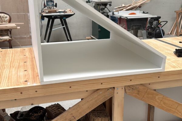 Primer módulo de un armario bajo escalera a medida fabricado en tablero hidrófugo lacado blanco durante la fase inicial de fabricación.